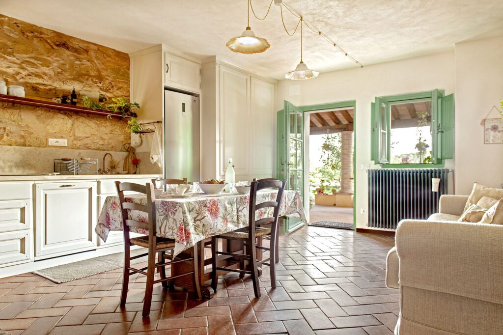 Cucina e zona pranzo con arredi rustici e porta francese verde - interni La Gualda Vecchia